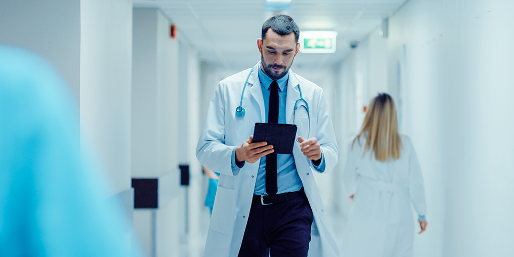 Doctor on ipad walking hospital hallway