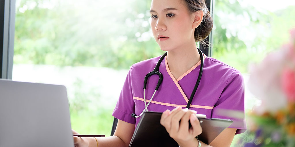 Nurse on computer with clipboard